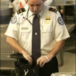 TSA employee looks inside laptop bag.